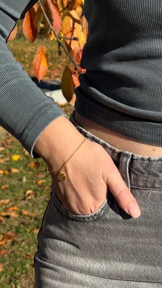 Golden charm bracelet shown on a woman's wrist with a close up view from O. Live Love.