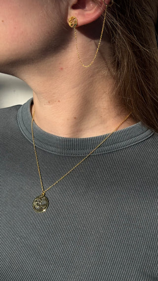 Golden charm necklace and earrings shown on a woman's neck from O. Live Love.